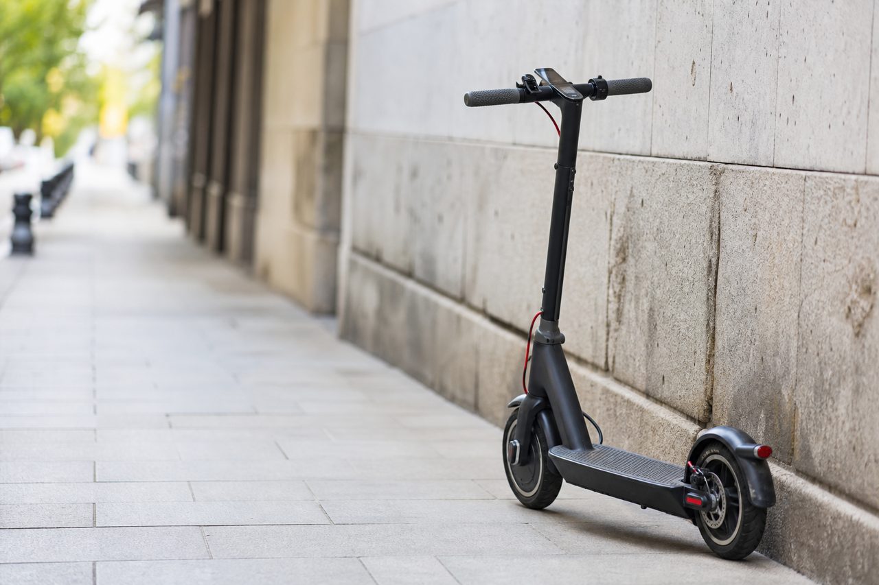 Trottinette électrique garée contre un mur en ville, batterie et écran de contrôle visibles