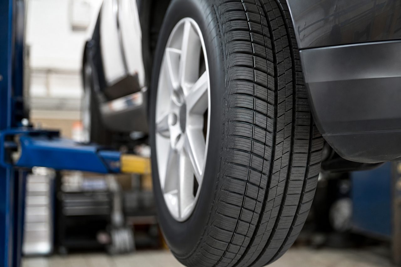Pneu de voiture neuf avec sculptures visibles, roue montée sur un véhicule dans un garage