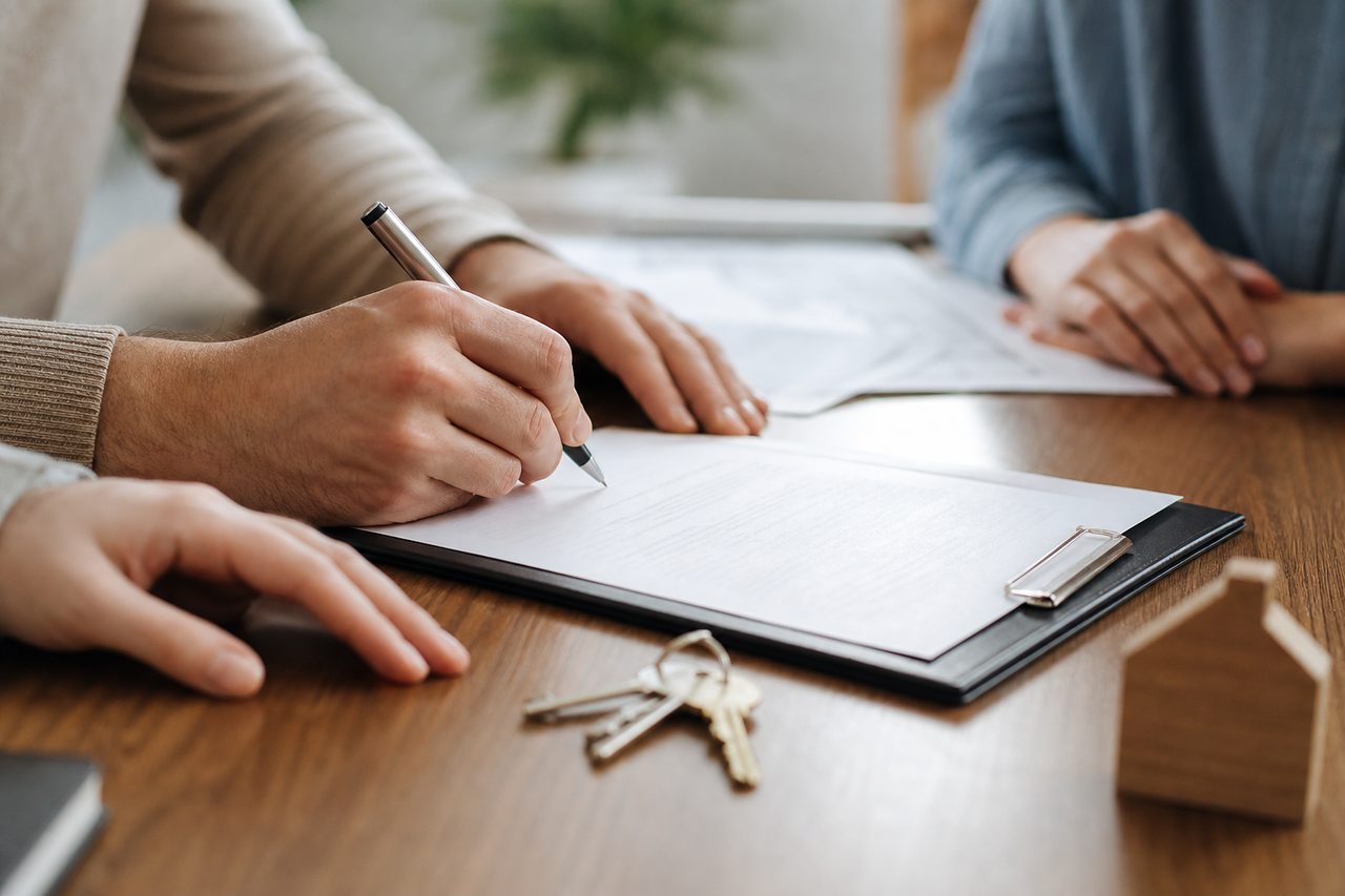 Clés de maison posées sur un contrat immobilier, lumière naturelle douce sur un bureau