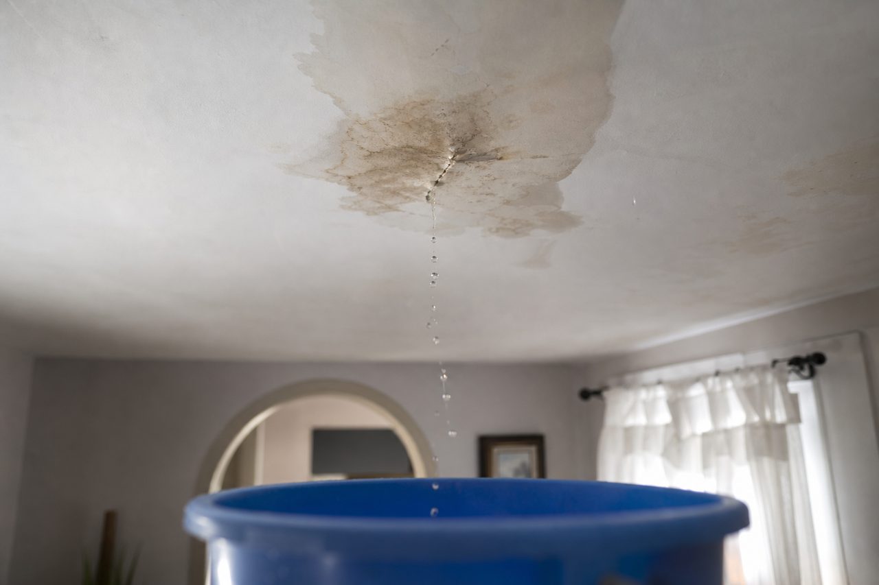 Plafond taché par une infiltration d'eau dans un appartement, avec un technicien qui inspecte les dégâts