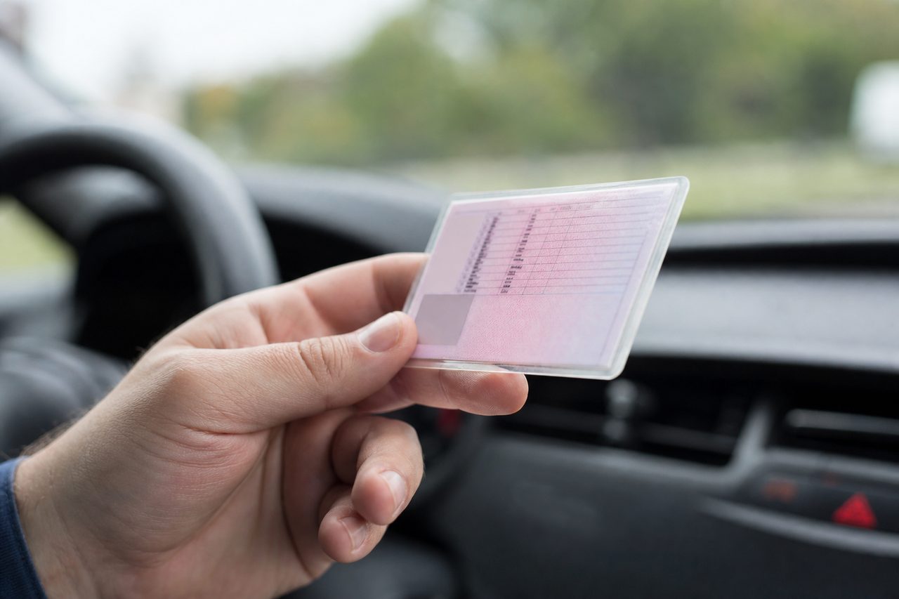 Permis de conduire français posé sur un tableau de bord de voiture, lumière naturelle douce