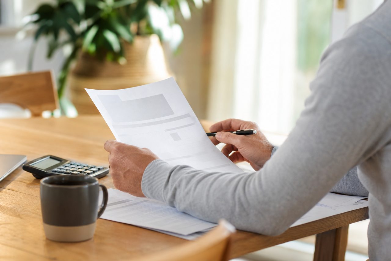 Particulier relisant une offre de crédit à la consommation à sa table, ambiance domestique posée